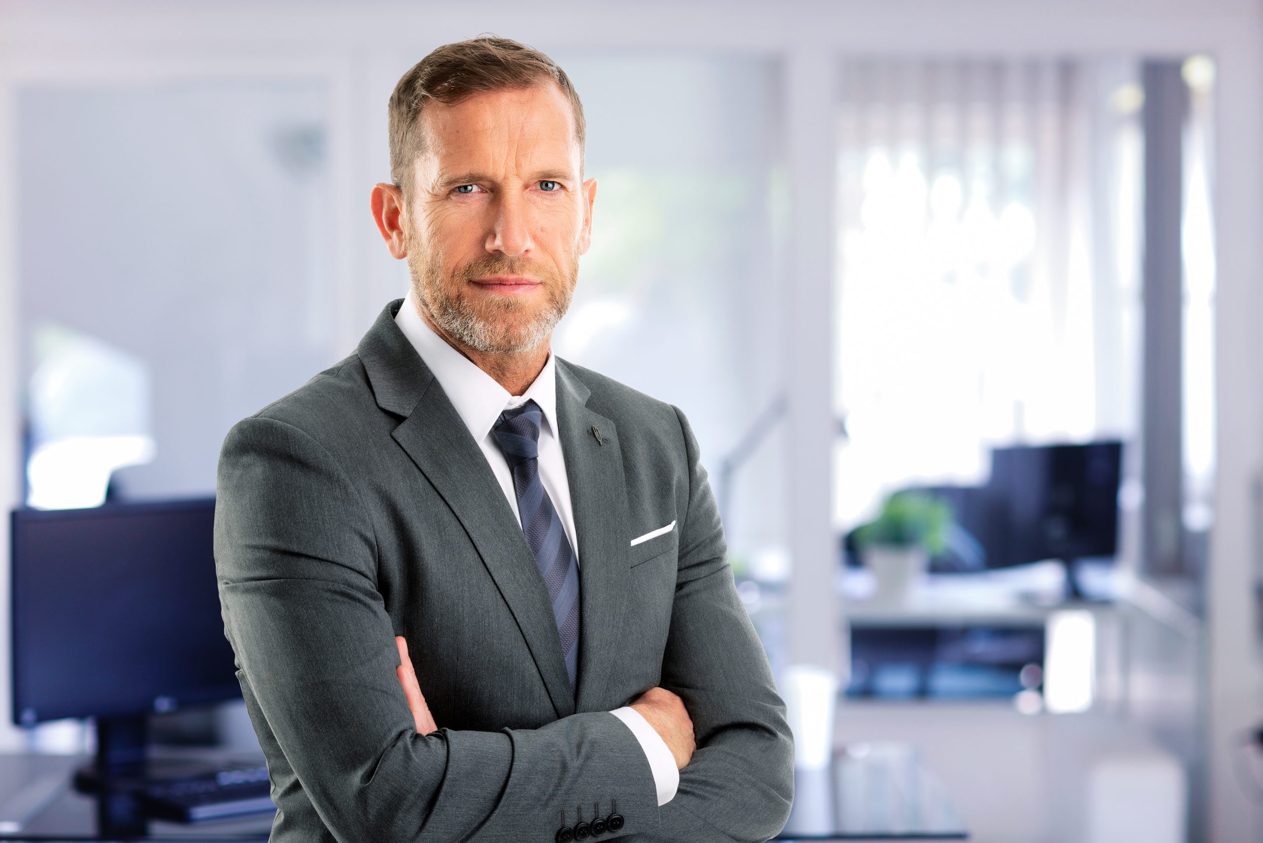 Senior businessman wearing suit and tie while standing at the office AdobeStock 580745249 1 scaled